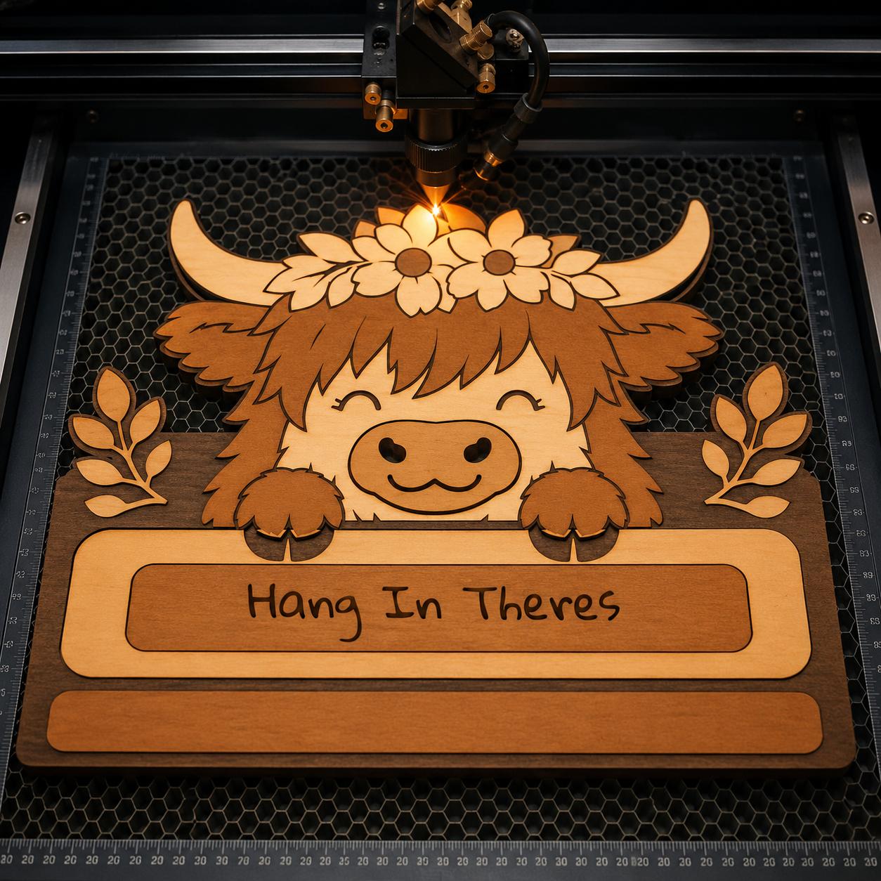 Laser cutting machine engraving a Highland Cow towel holder SVG file with floral crown details for Glowforge, CNC, and laser cutting projects.