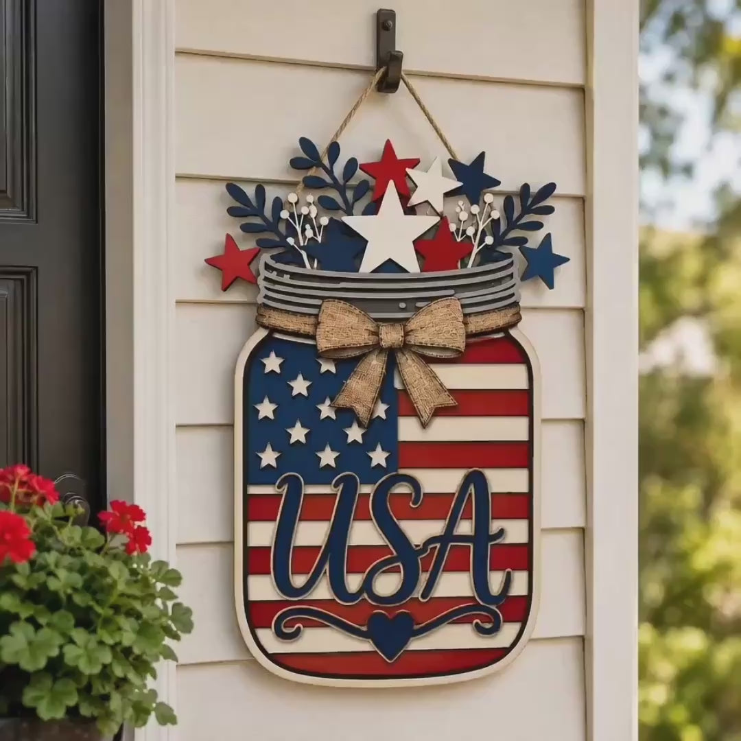 Layered USA American Flag Mason Jar laser cut sign displayed as patriotic farmhouse decor. 3D wooden mason jar design featuring stars, stripes, rustic bow, and red white blue accents, perfect for front door decor, porch decorations, and 4th of July home decor. Compatible with Glowforge, xTool, LightBurn, Cricut, and other laser cutting machines.