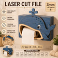 Blue whale toilet paper holder laser cut file mounted on a bathroom wall, featuring a playful whale mouth design that dispenses toilet paper. Creative SVG template for Glowforge, xTool, LightBurn, Cricut, and woodworking projects.